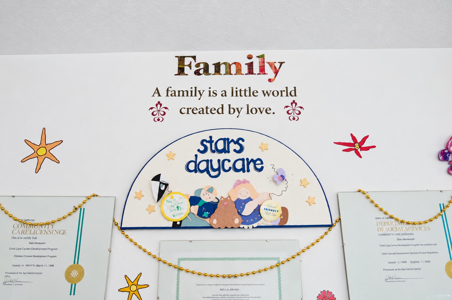 A family-themed wall display and licensing certificates at Stars Childcare